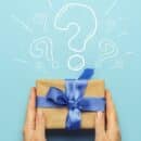 A paper-wrapped gift with a blue bow with a question mark above it.