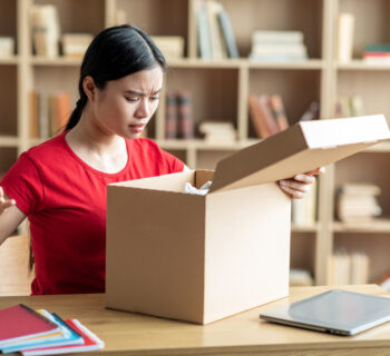 A frustrated young woman wearing a red shirt realizes she make a mistake on her personalized gift order.