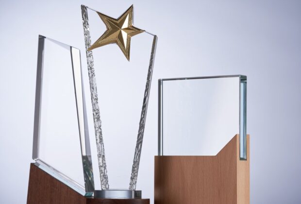 Three crystal plaques in different shapes and sizes are on a table. The middle plaque has a gold star on top.